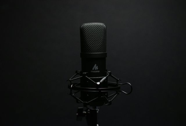 Studio microphone with shock mount on a dark backdrop, perfect for audio recording setups.