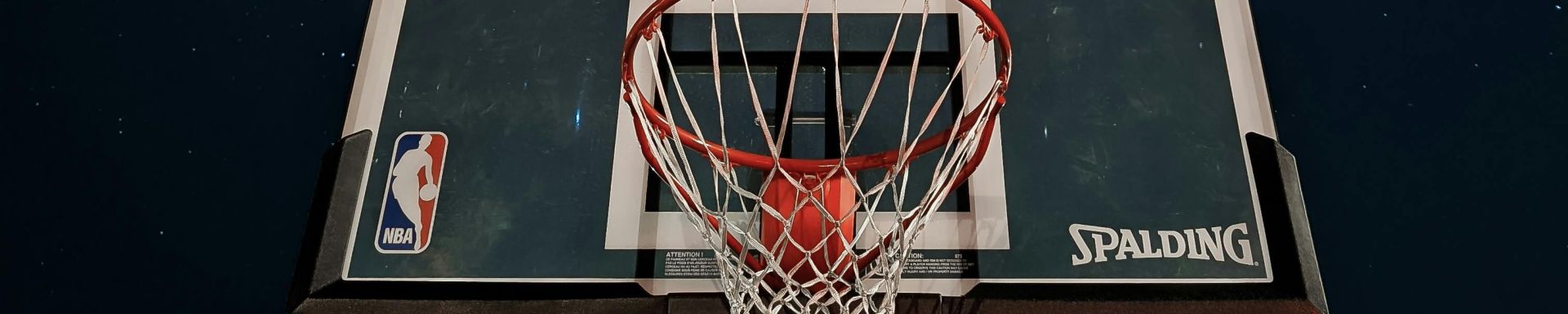 A basketball hoop silhouetted against a dark night sky filled with stars.