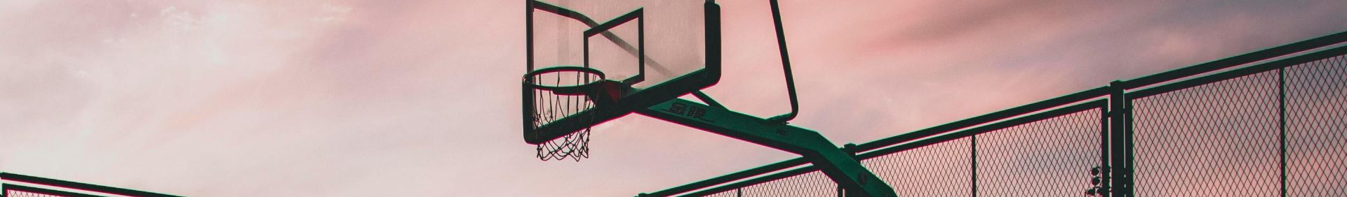 A tranquil view of a basketball court with reflections during sunset, creating a serene urban landscape.
